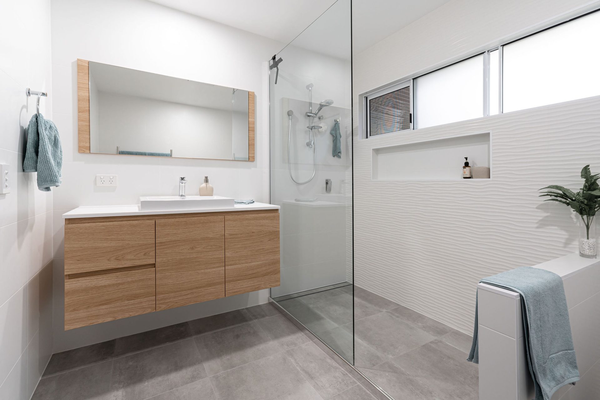 Minimalist bathroom design with freestanding white bath, concrete floor and floating cabinetry