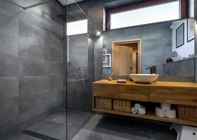 Modern bathroom with large floor to ceiling tiles, glass shower and timber vanity