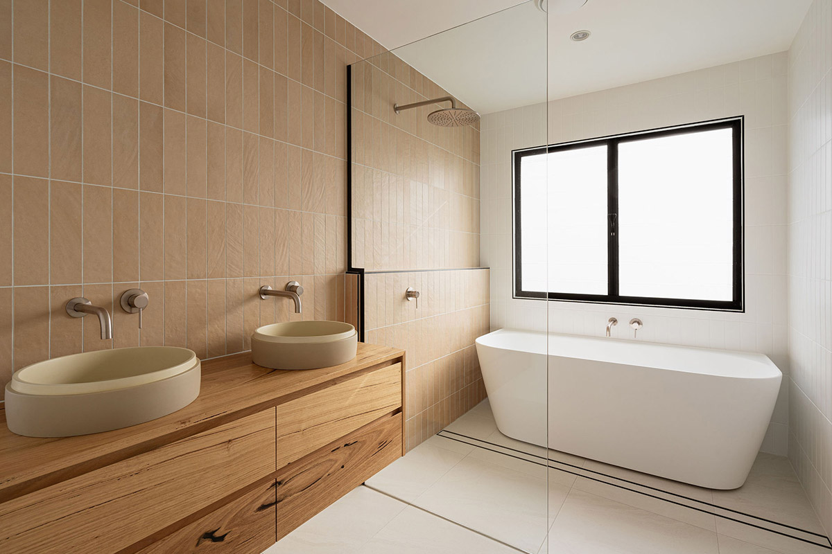 Luxury bathroom with vertical tiles, twin sinks and timber cabinetry