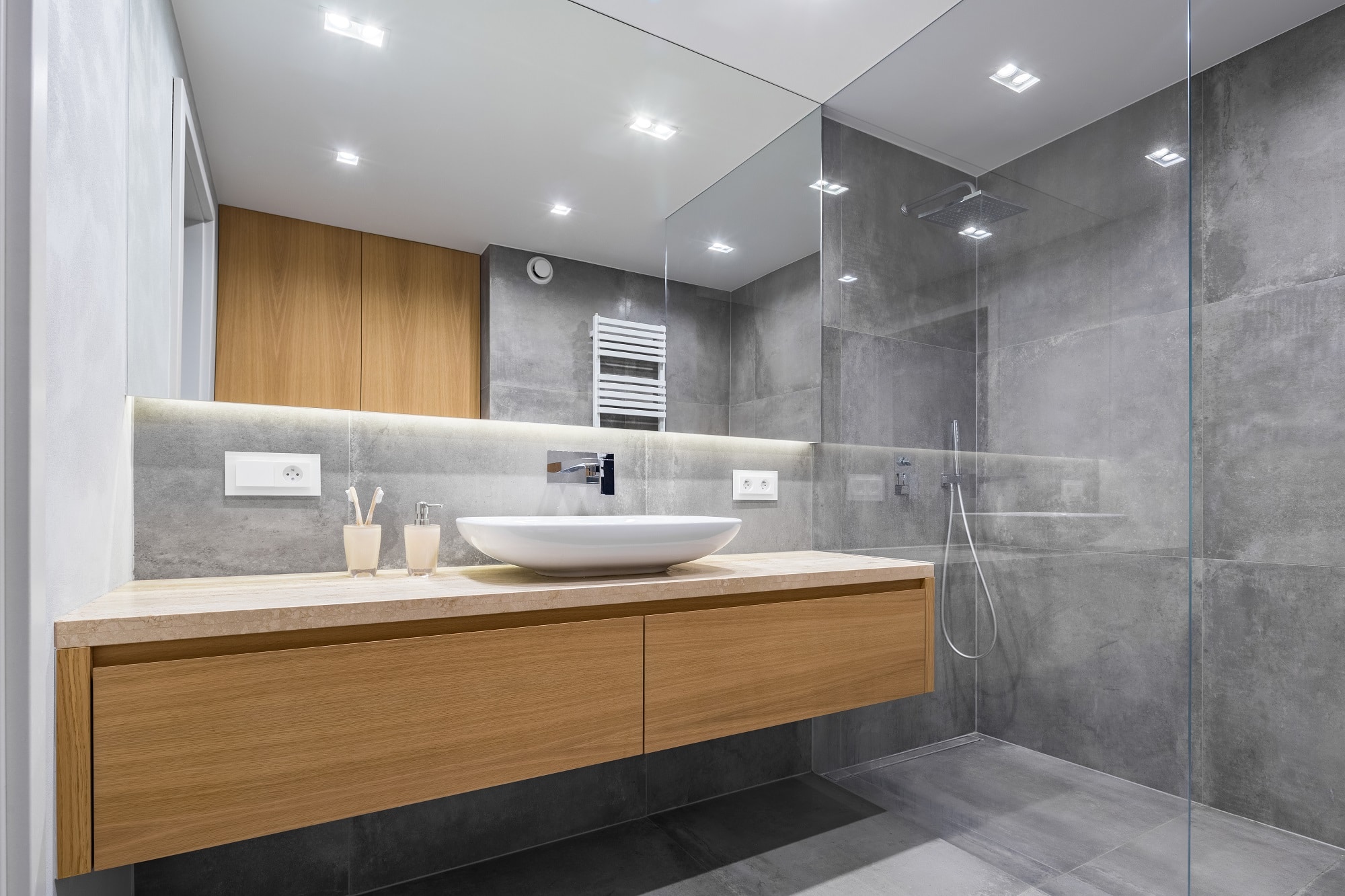 Modern bathroom with large format concrete-look tiles, stepless shower and timber cabinetry with stone top
