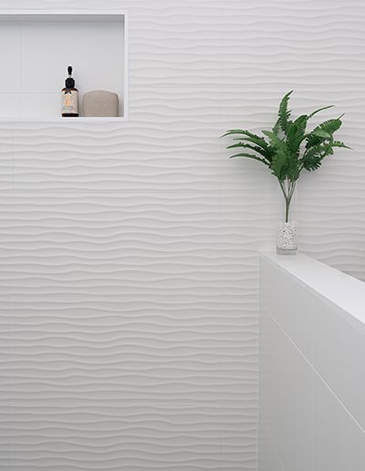 Rippled white shower feature wall with niche.