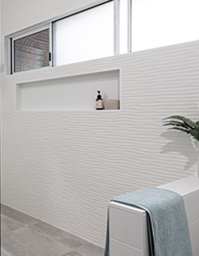 White shower feature wall with niche and wide window above.